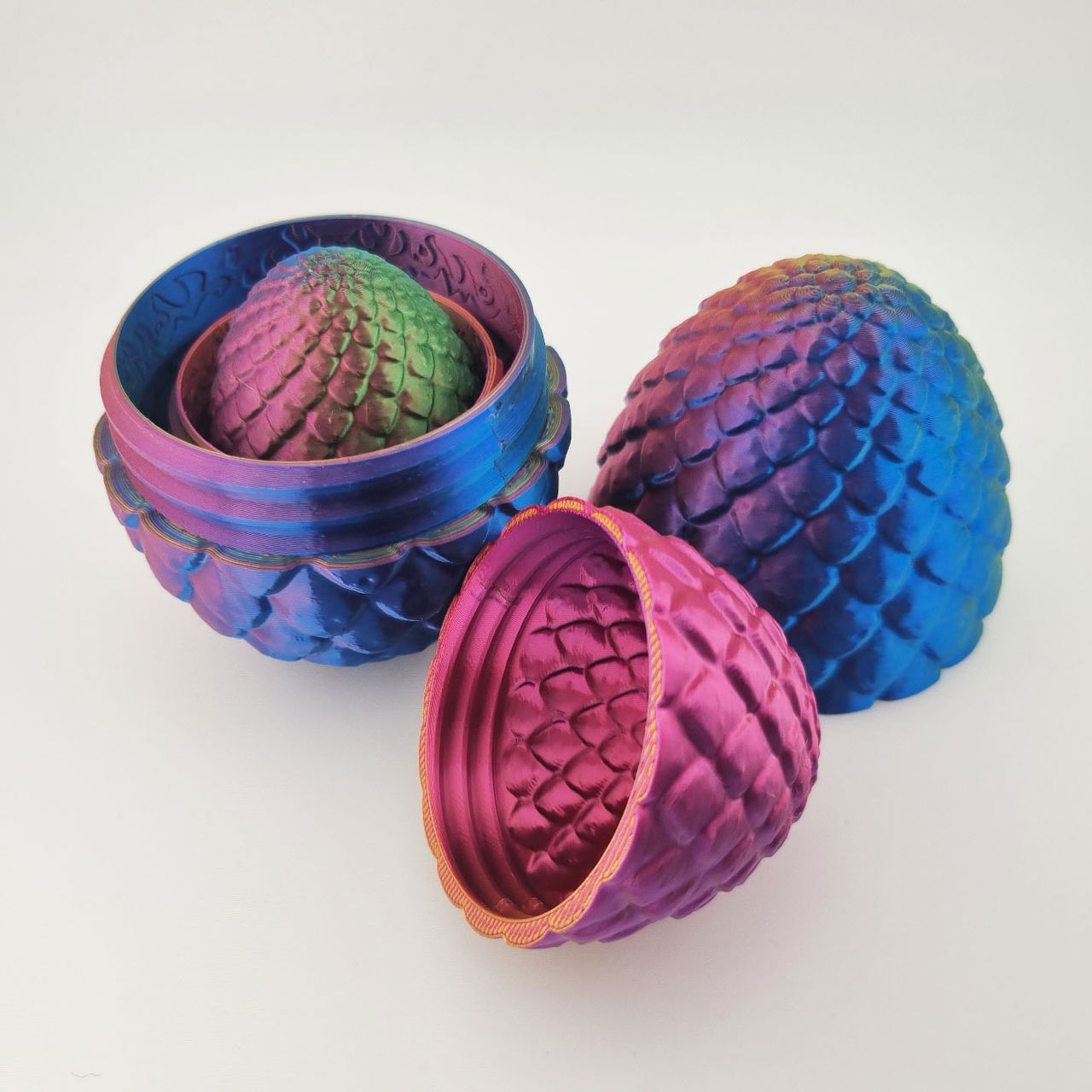 3D-printet drageæg i blå, pink og grøn med skæl og aftagelige dele.