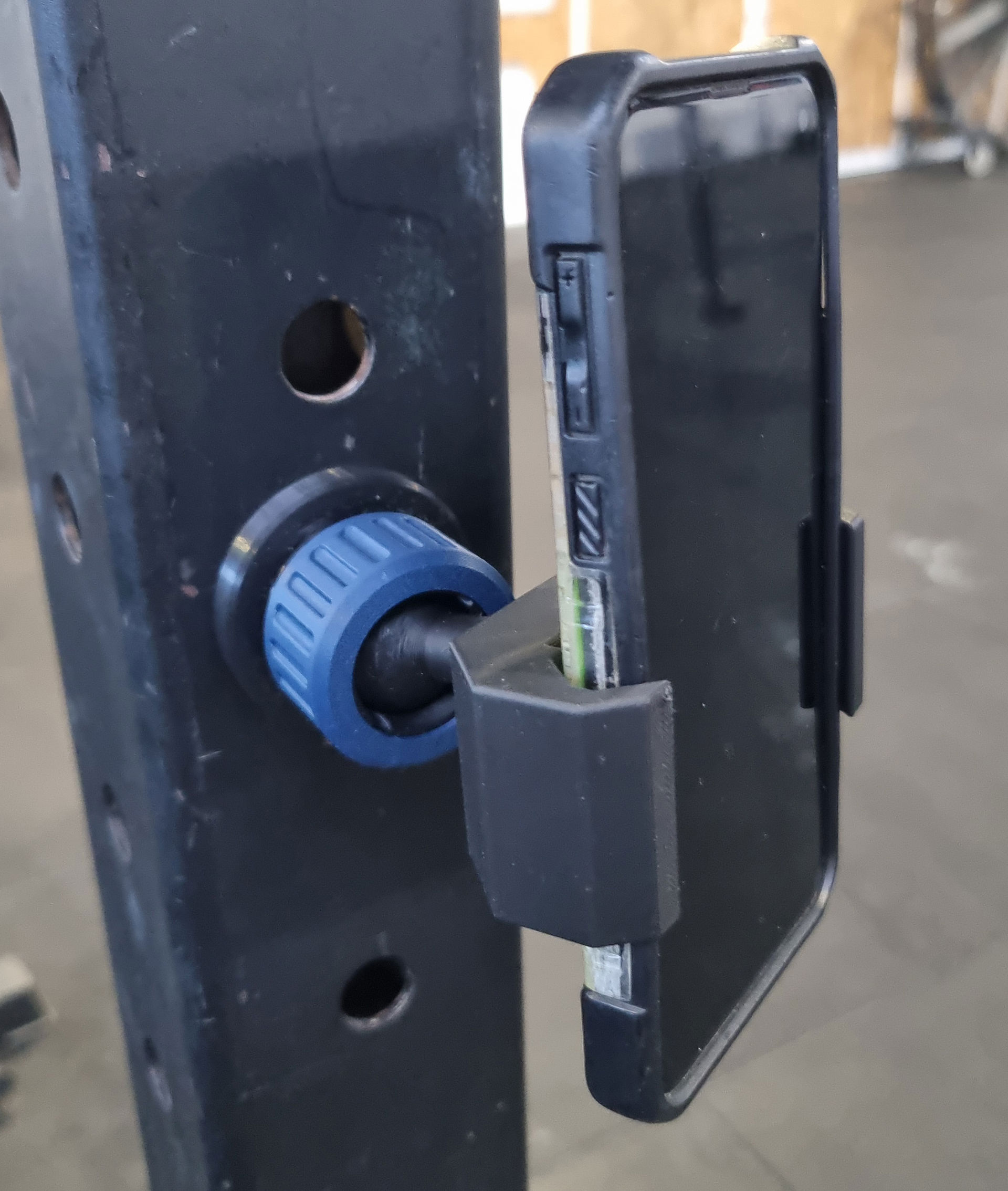 Sort magnetisk mobilholder med blå drejeknap monteret på metalstolpe.