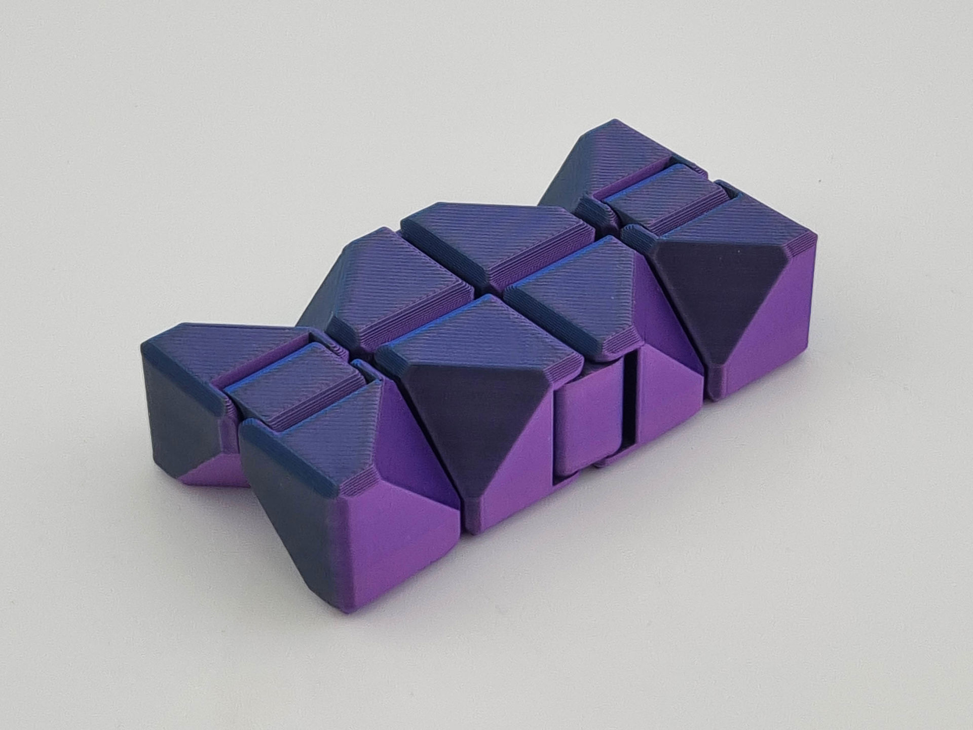 Lilla og mørkeblå 3D-printet fidget cube med sammenhængende, drejelige led.