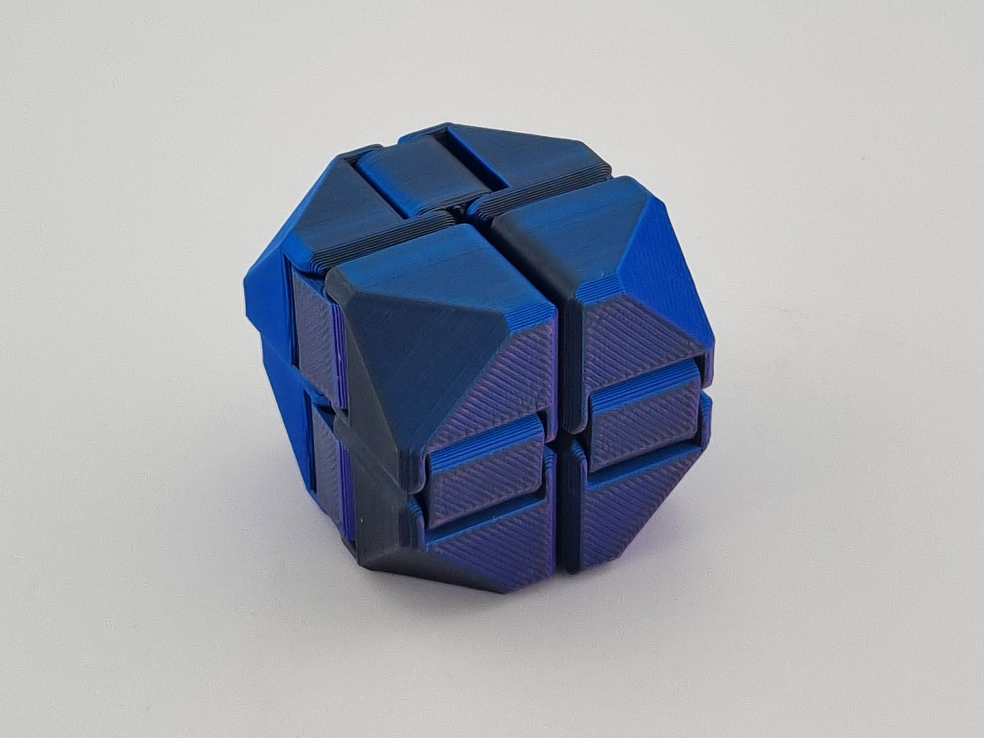Blå 3D-printet fidget cube med hængslede, geometriske led.