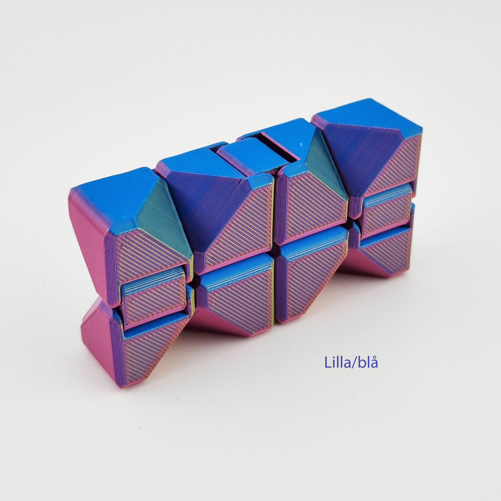 Lilla-blå 3D-printet fidget cube med hængslede, trekantede led. Tekst: Lilla/blå.