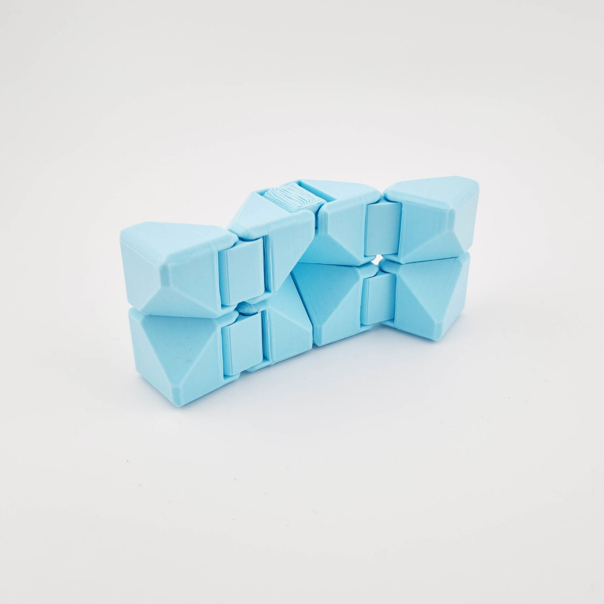 Lyseblå fidget cube med hængslede, geometriske led delvist udfoldet.