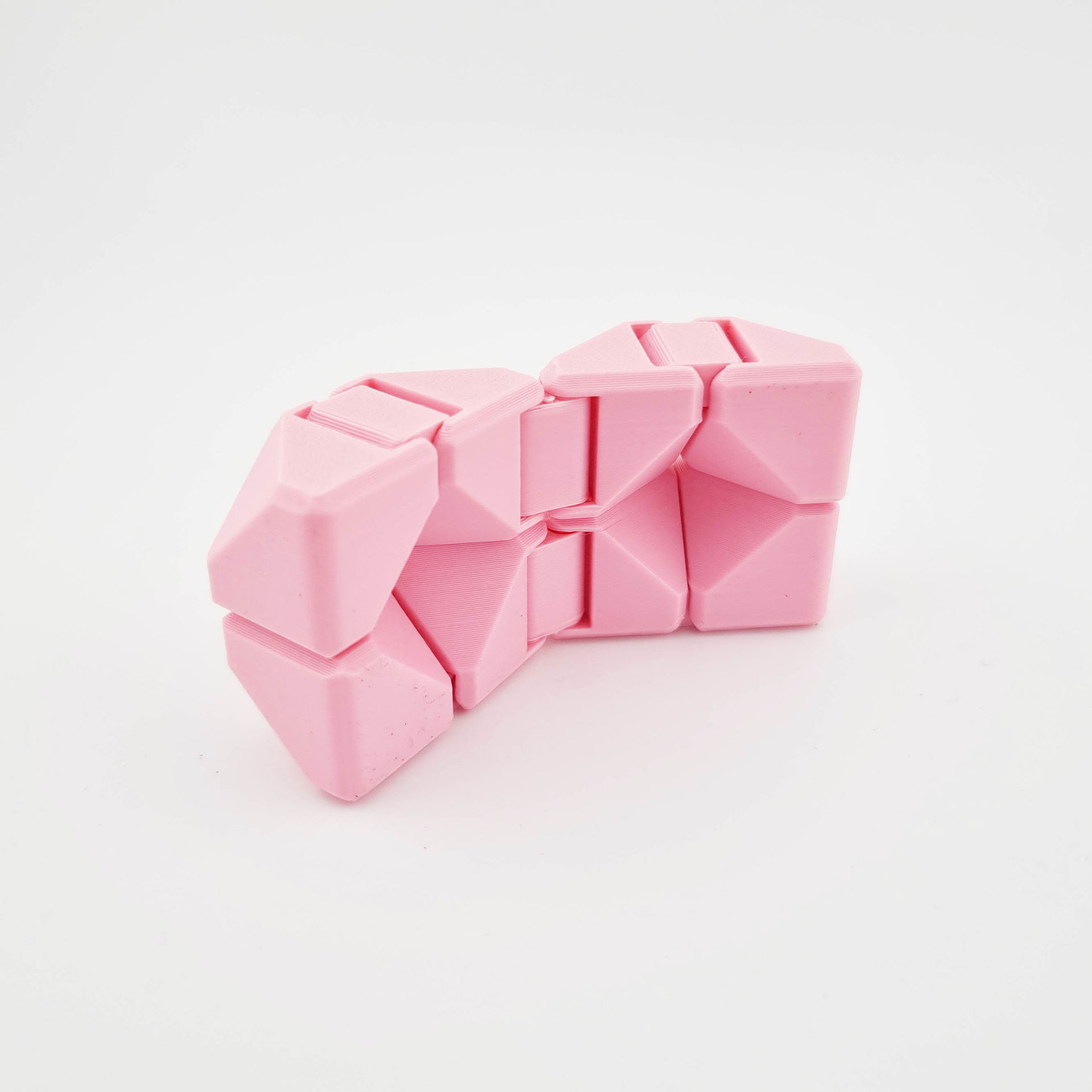 Lyserød 3D-printet fidget cube med sammenfoldelige, geometriske led.