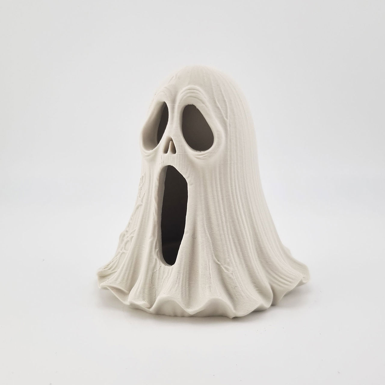 Hvid 3D-printet spøgelsesfigur med sorte øjne og åben mund.