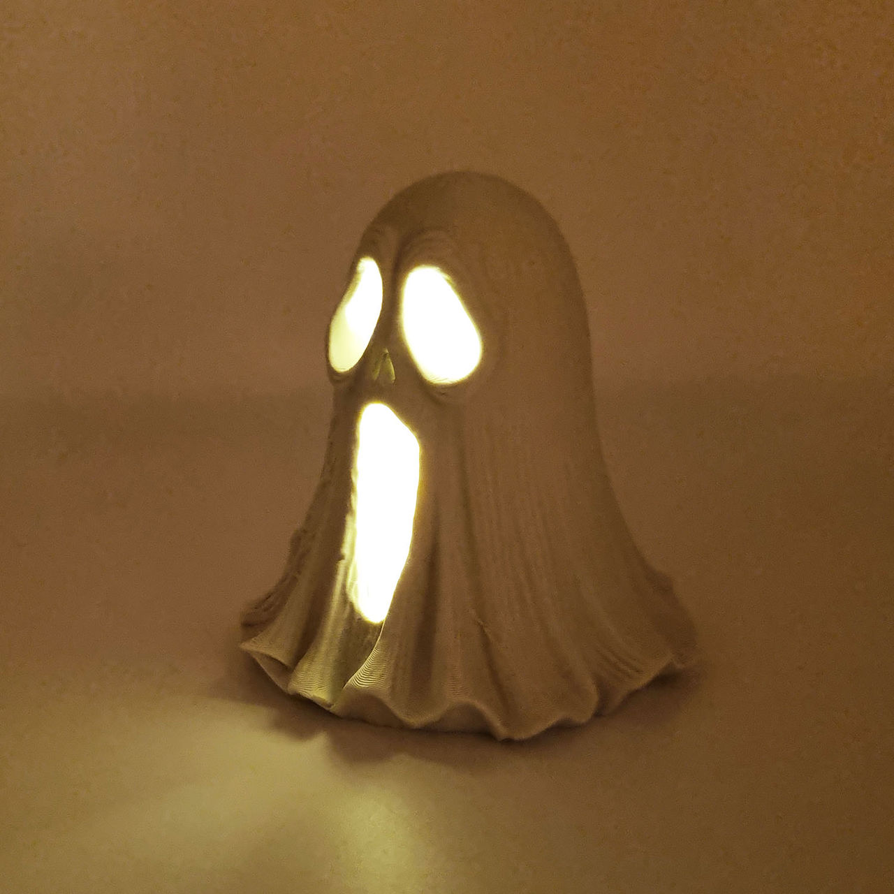 Hvid 3D-printet spøgelseslampe med lysende øjne og åben mund.