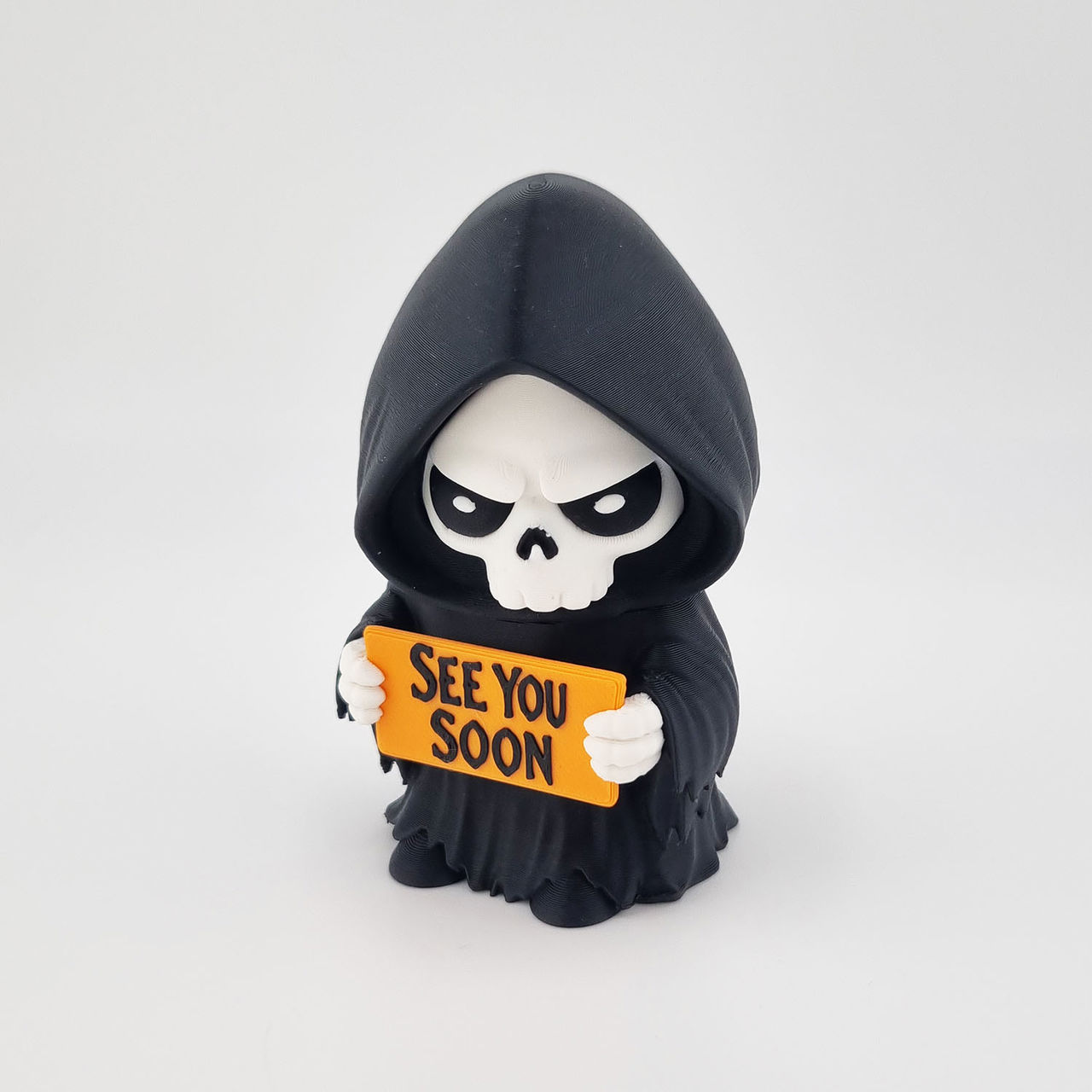 Sort hætteklædt grim reaper holder orange skilt med teksten "SEE YOU SOON".