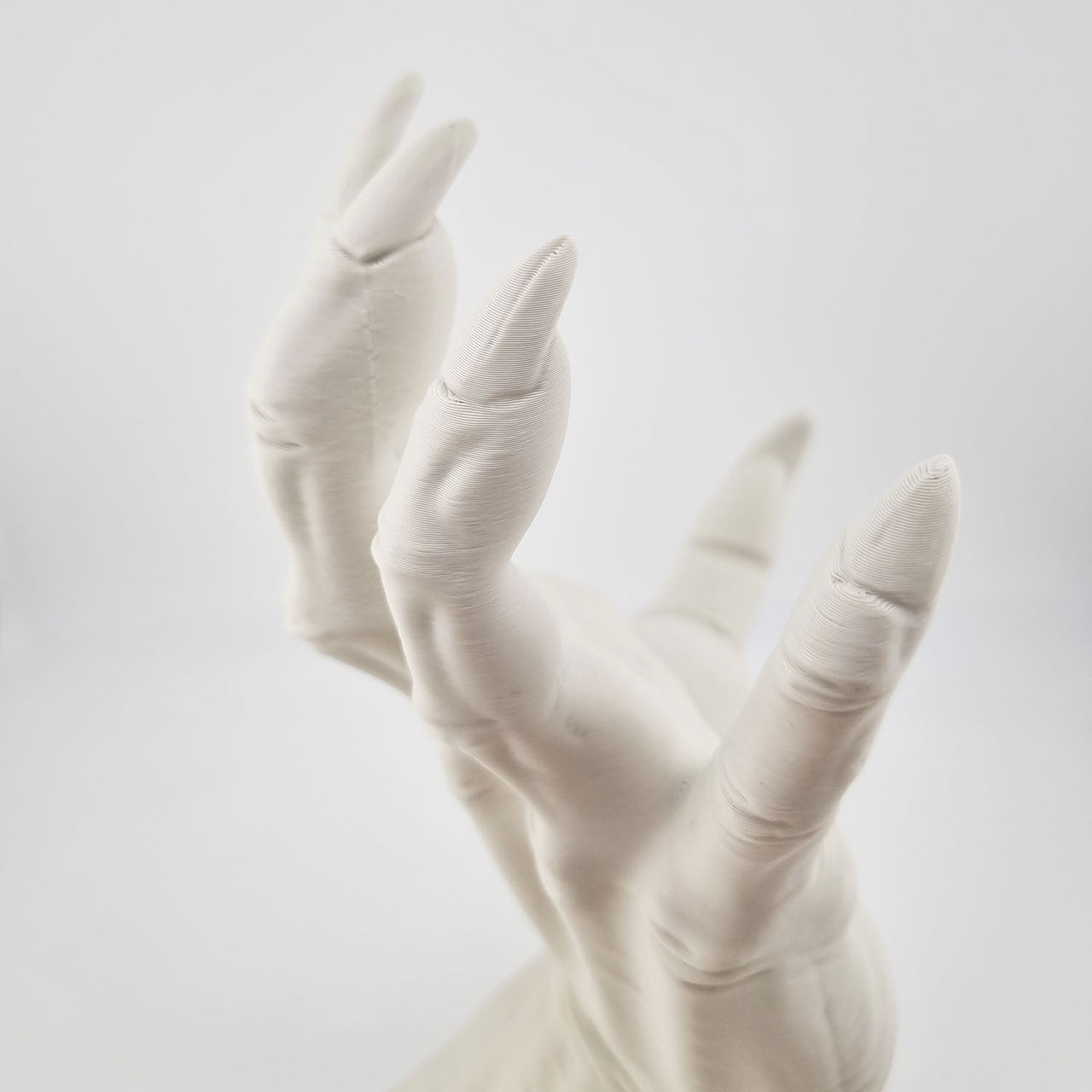 Hvid 3D-printet klo med fire spidse fingre og synlige laglinjer.