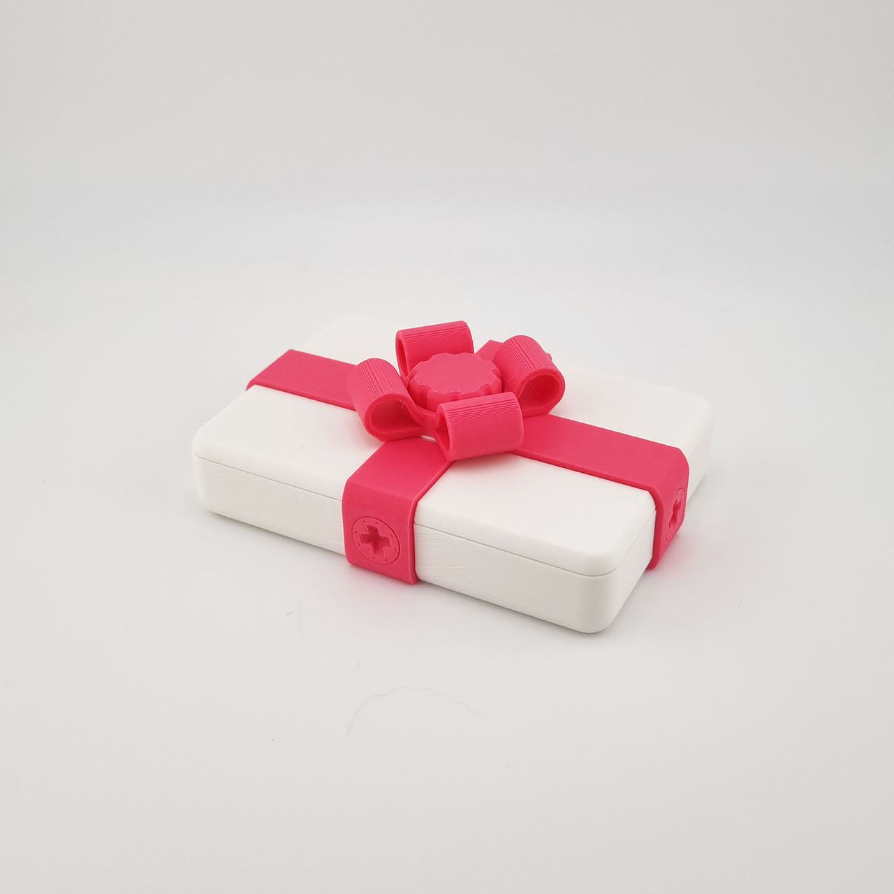 Hvid 3D-printet gaveæske med pink bånd og sløjfe.