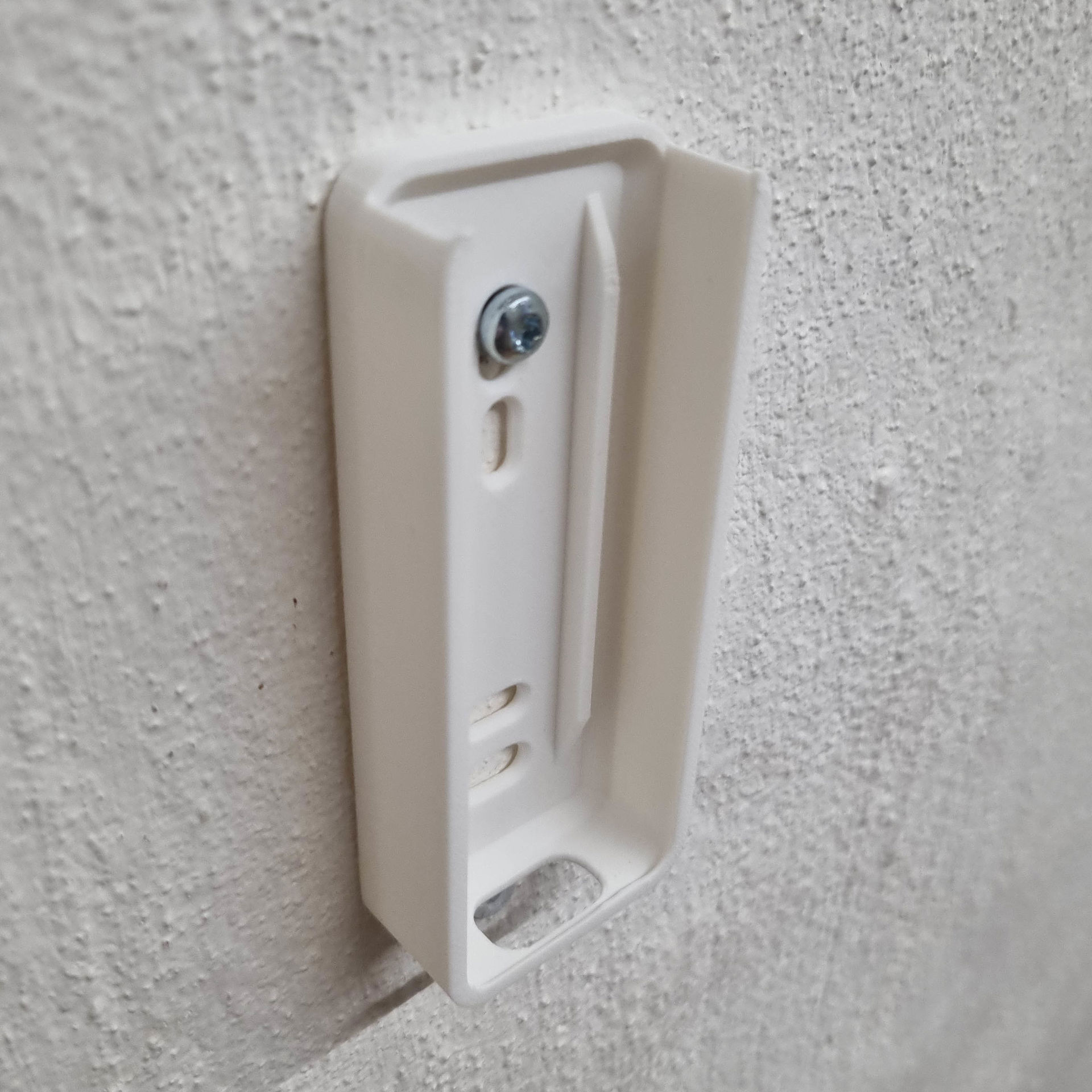 Hvid Hue Dimmer Switch V2-holder monteret på væg med synlig skrue.