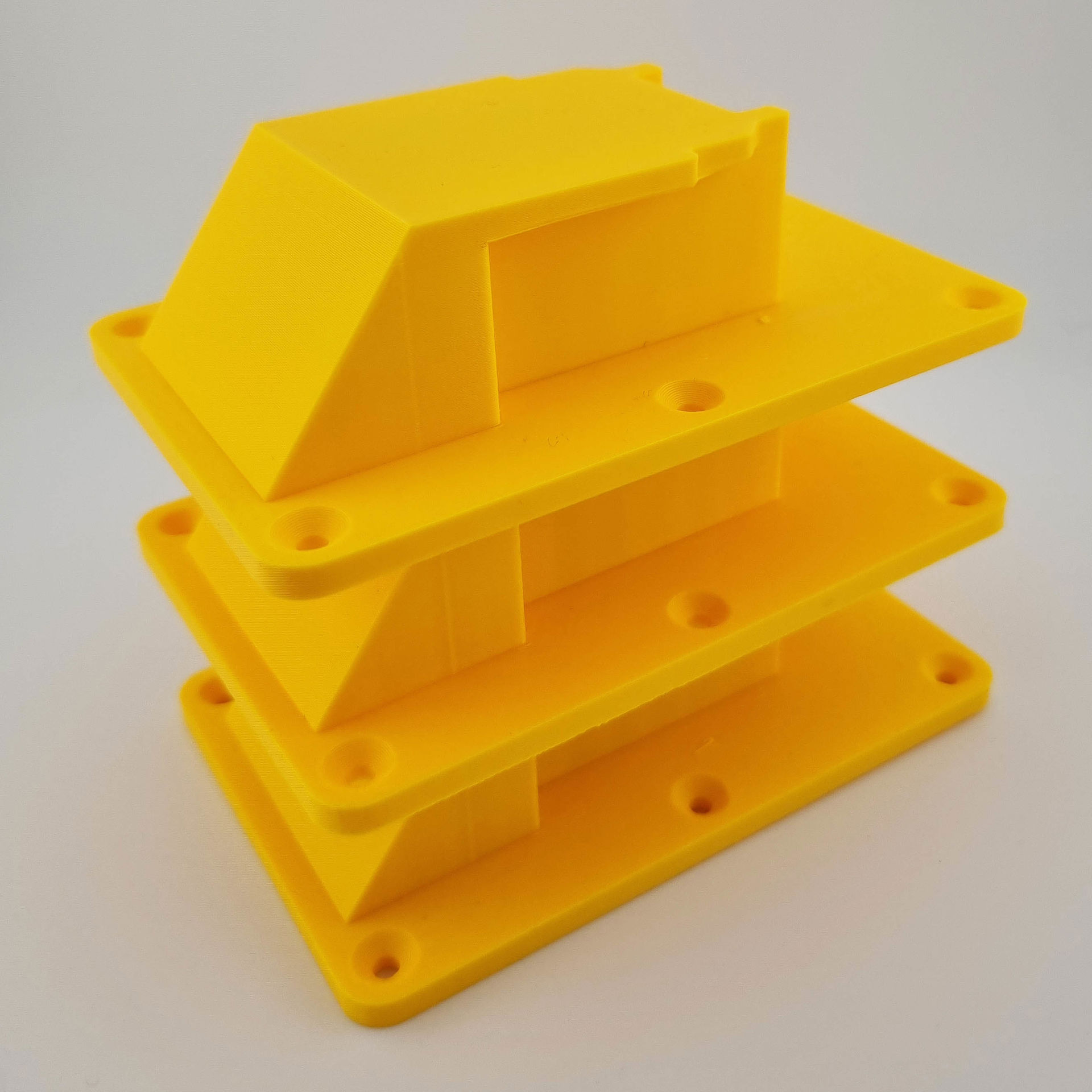 Tre gule DeWalt 18V/20V værktøjsholdere med skruehuller, stablet oven på hinanden.