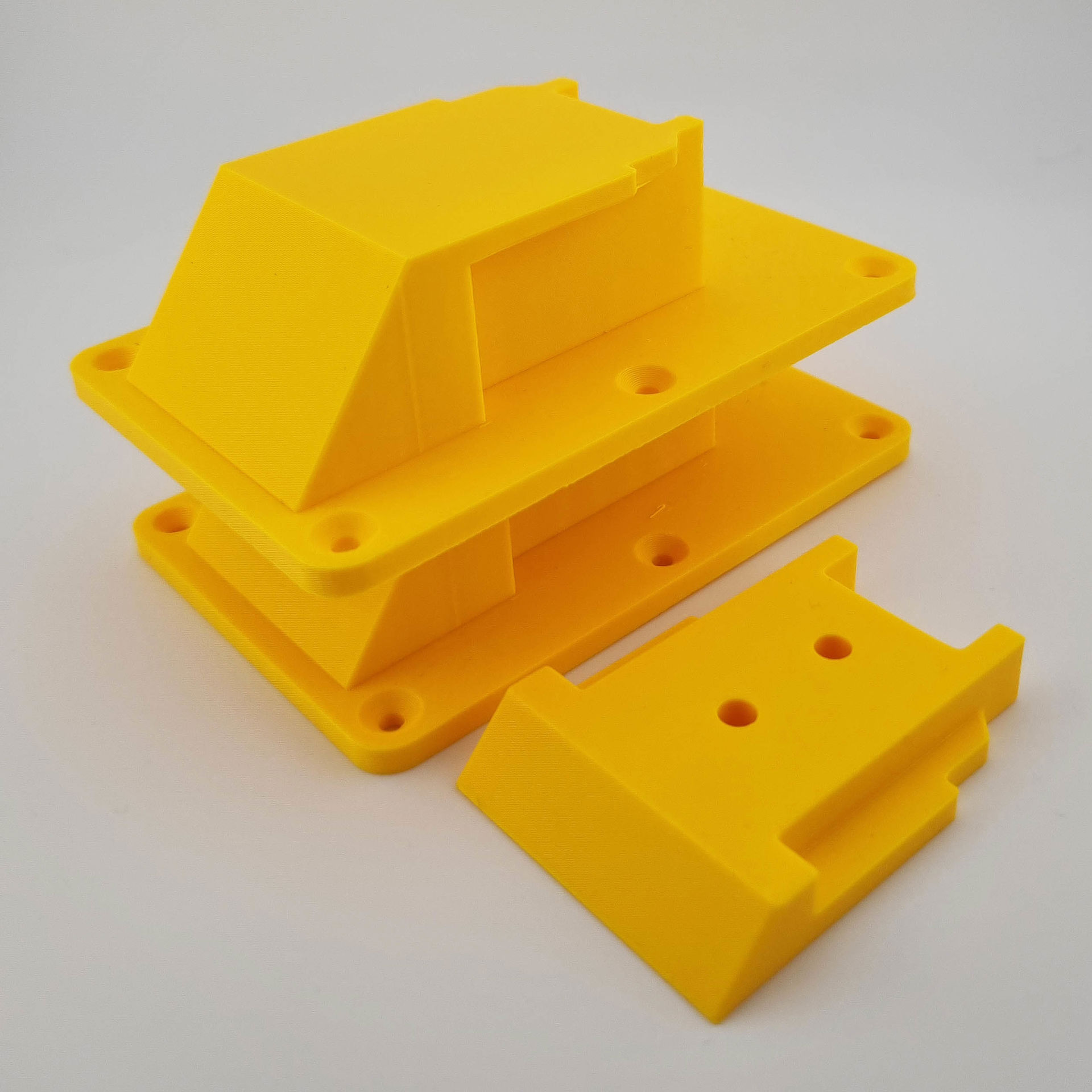 Tre gule DeWalt 18V/20V-værktøjsholdere med skruehuller og skinner.