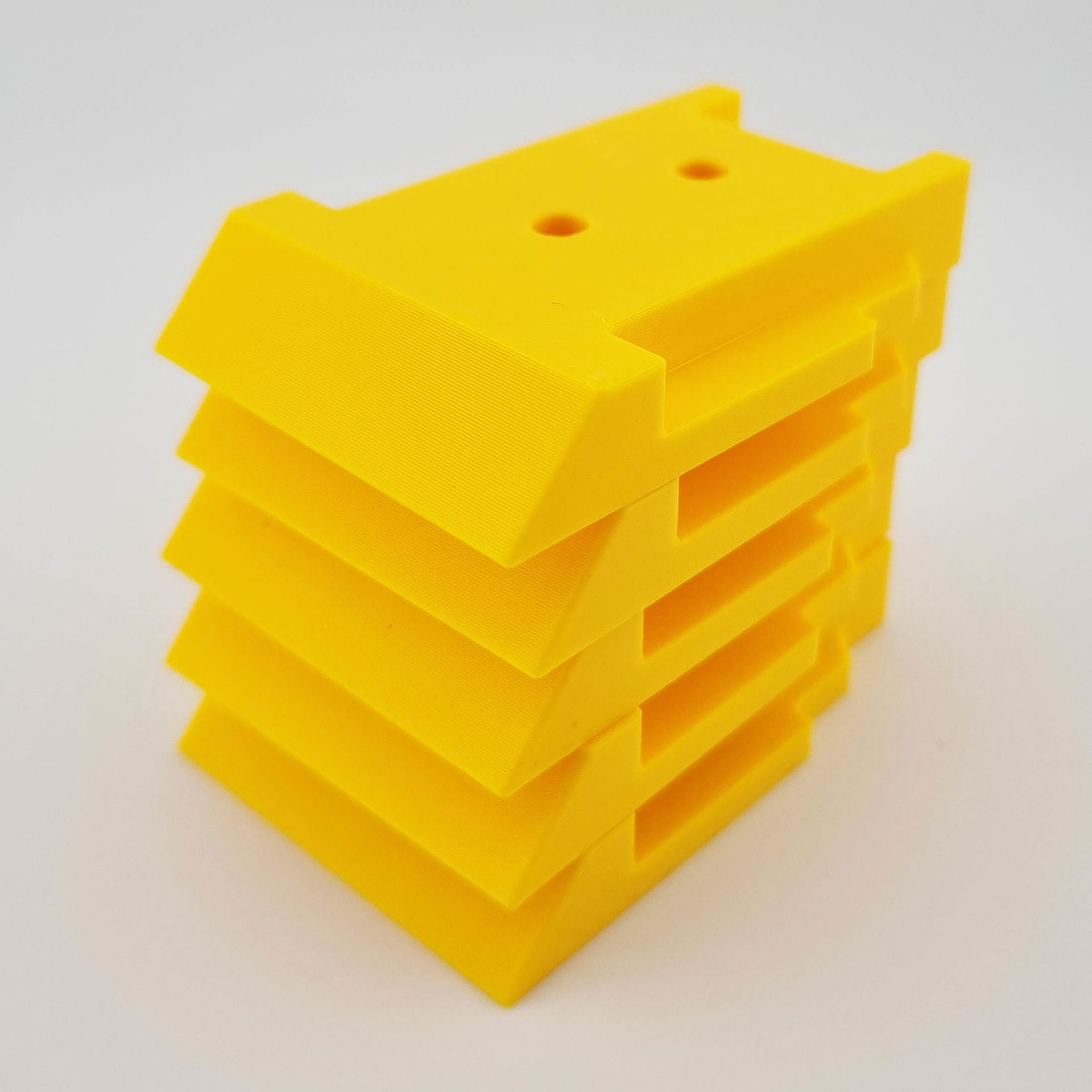 Fire gule 3D-printede DeWalt 18V/20V-værktøjsholdere stablet oven på hinanden.